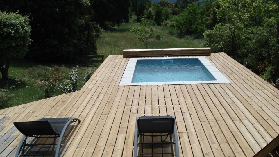 Piscine béton avec bâche à barres et plage bois