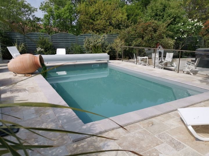 Piscine béton volet hors sol et plage travertin